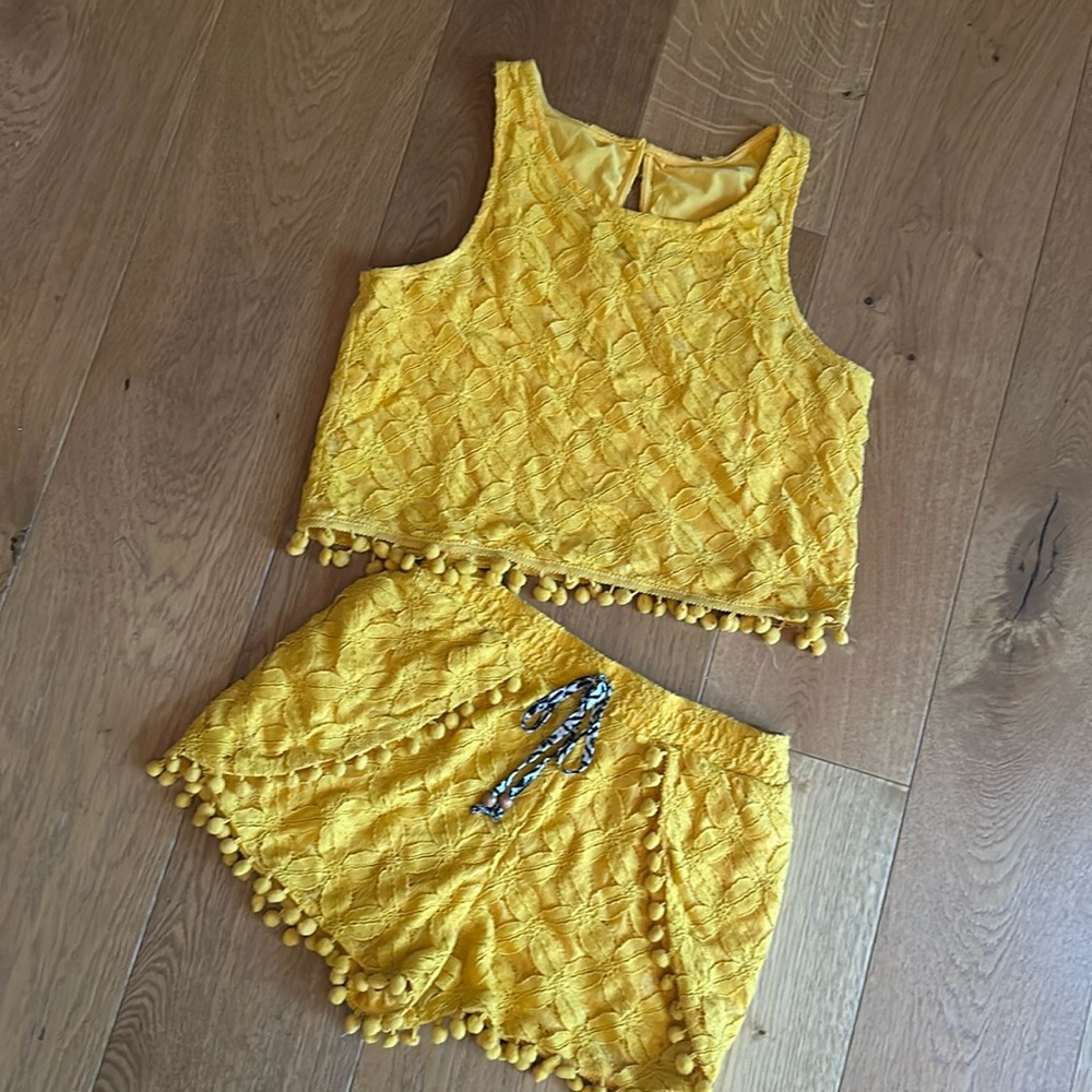 Boho style bright yellow, crop top and matching shorts with pom-poms.